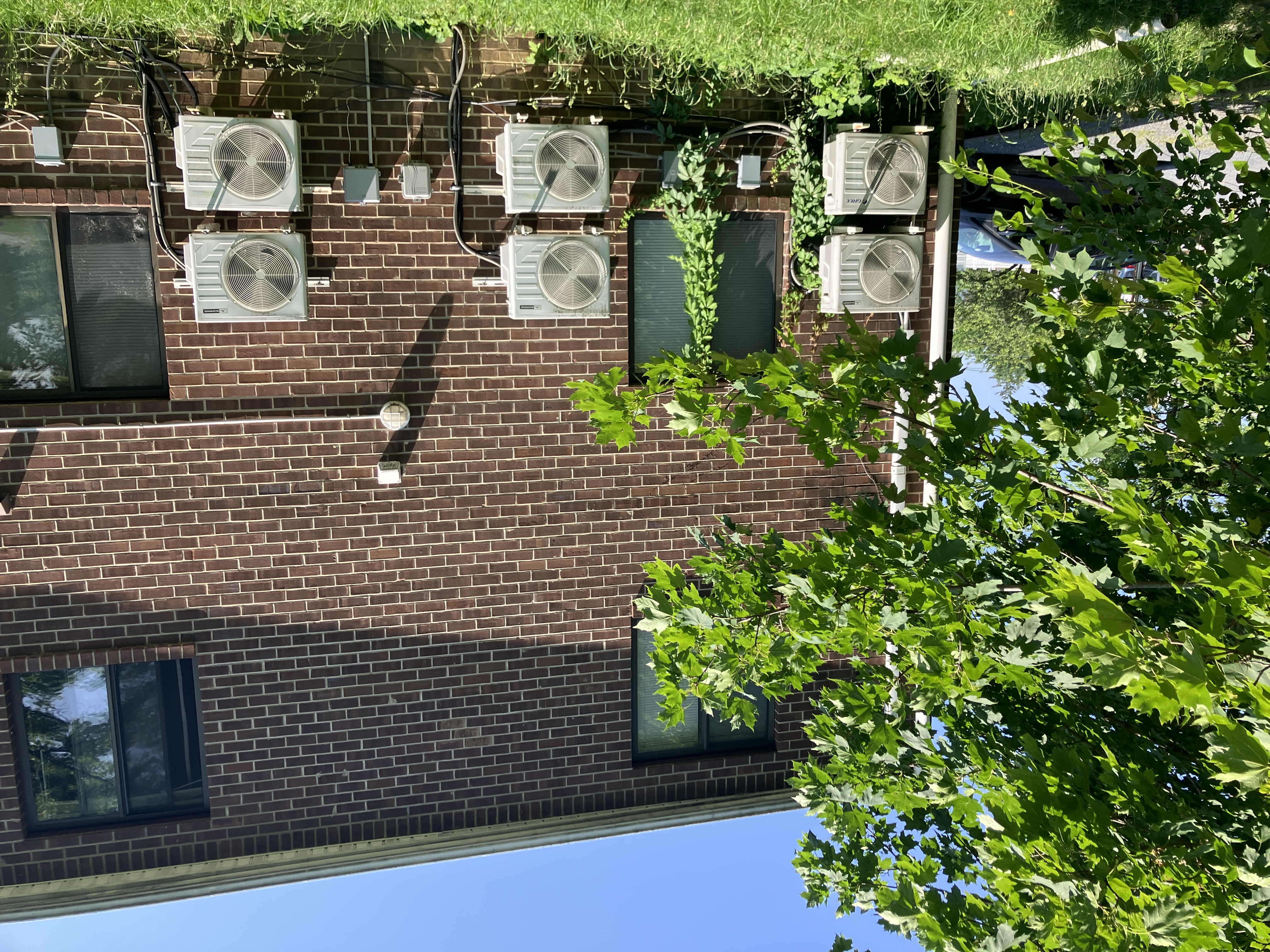 Brick apartment building shaded by mature trees